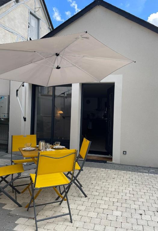 une table avec des chaises jaunes et un parasol dans l'établissement L'Archevêché : Au pied de la cathédrale, à Bourges