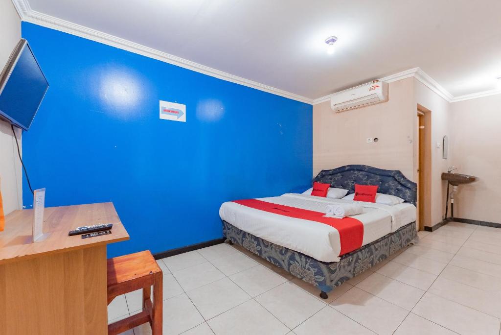 a bedroom with a blue wall and a bed with a desk at RedDoorz Syariah At Cibadak Sukabumi in Sukabumi