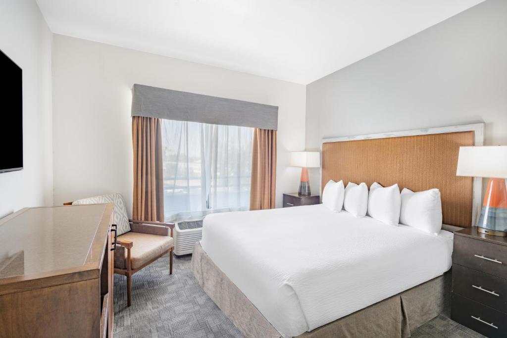 Una habitación de hotel con una cama grande y un escritorio. en Ramada by Wyndham Bakersfield, en Bakersfield