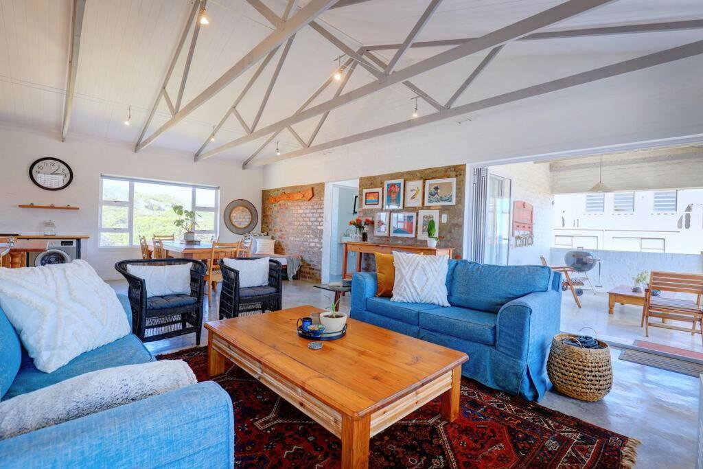 ein Wohnzimmer mit blauen Sofas und einem Tisch in der Unterkunft Jolie Beach Apartment in Wilderness