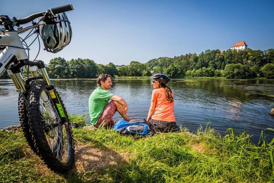 un homme et une femme assis près d'une rivière à côté d'un vélo dans l'établissement Ferienwohnung Neuhaus, à Nittenau