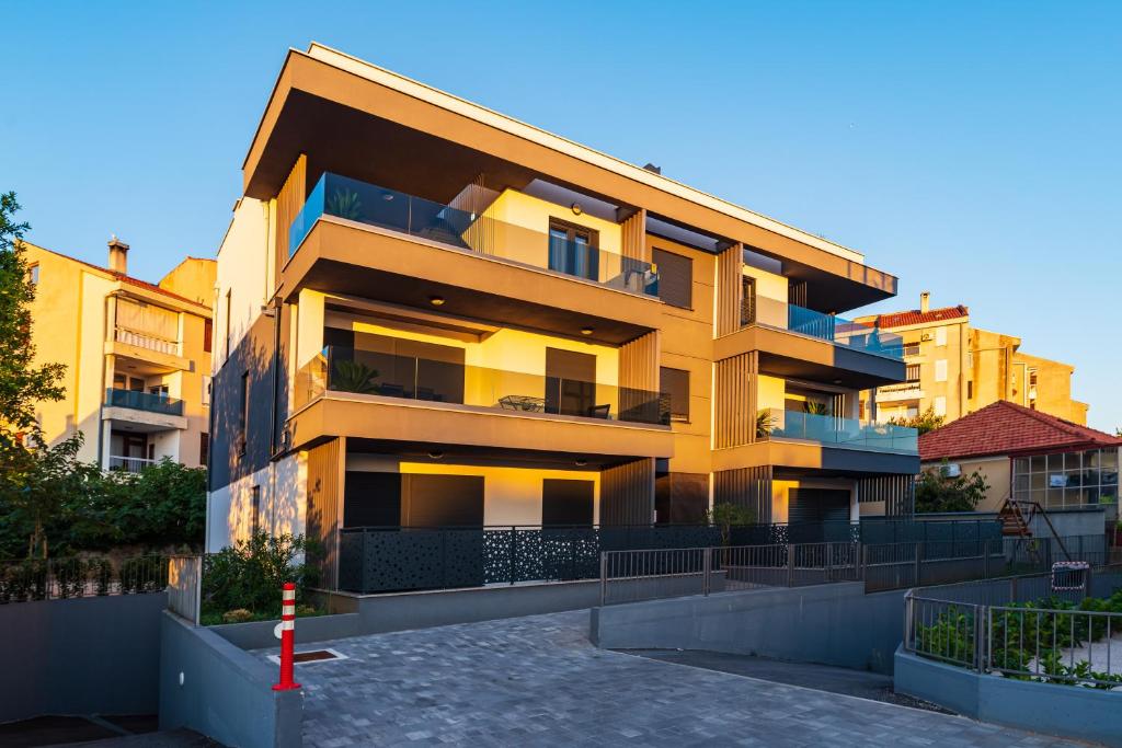 een geel appartementencomplex met een parkeerplaats bij Apartment Dalmo Views in Zadar