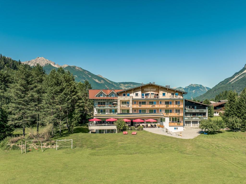 a large building with mountains in the background at Hotel Föhrenhof in Stanzach