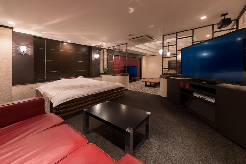 a living room with a bed and a large screen tv at ホテルＫＩＮＧＤＡＭ in Osaka