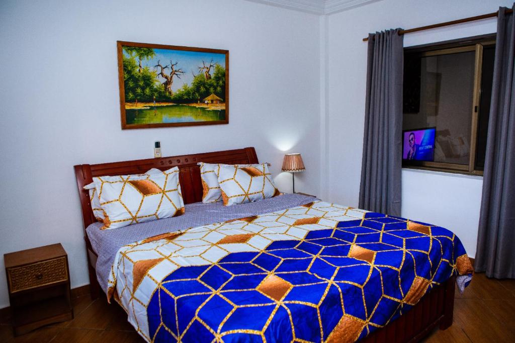 - une chambre avec un lit bleu et blanc et une fenêtre dans l'établissement Luxor garden apartments, à Accra