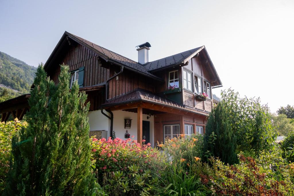 a wooden house with flowers in front of it at Haus Seegarten in Grundlsee
