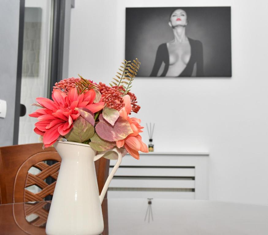 um vaso branco com flores sobre uma mesa em Apartament Luxury - Promenada Mall em Craiova