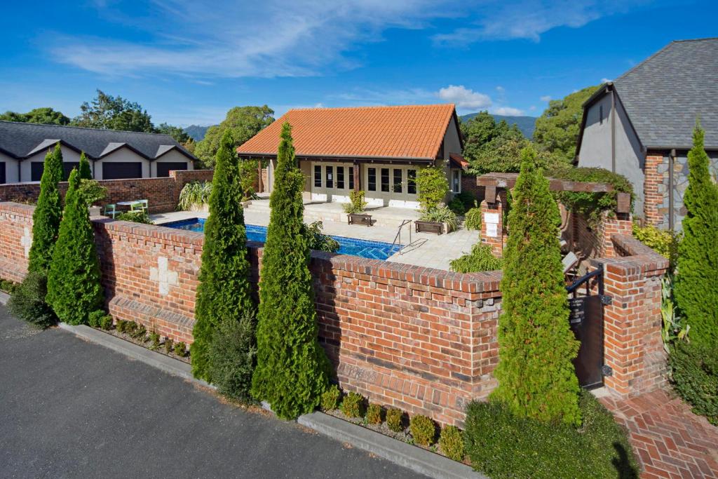 uma vista aérea de uma casa com uma parede de tijolos e uma piscina em Monaco Poolside Apartment em Nelson
