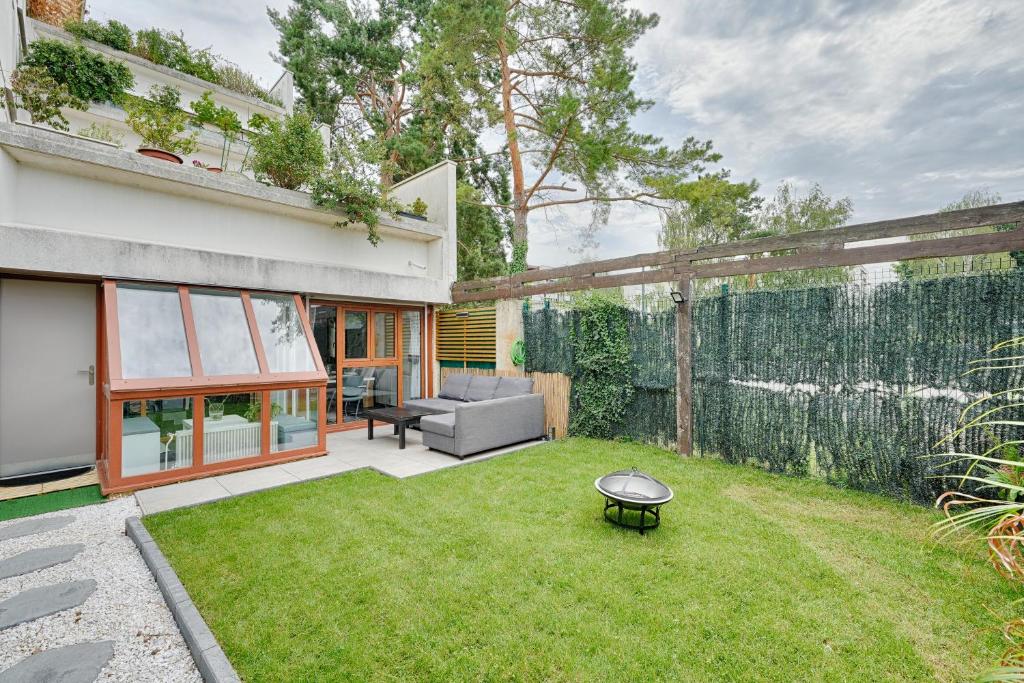 um quintal com um sofá e uma mesa na relva em Le 44 - Appt avec jardin privé em Ris-Orangis