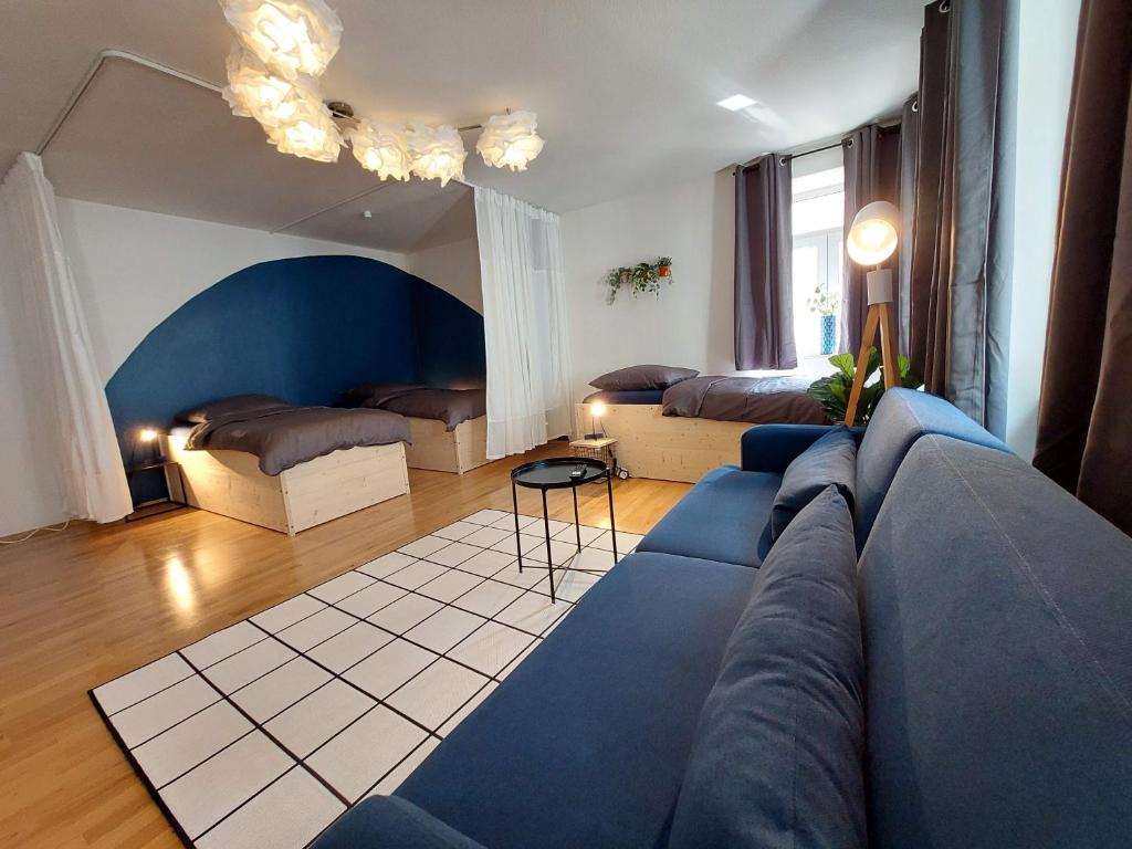 a living room with a blue couch and two beds at Viel Platz für Gruppen inkl. Waschmaschine, Hochstuhl und Playstation mitten in der Altstadt in Amberg