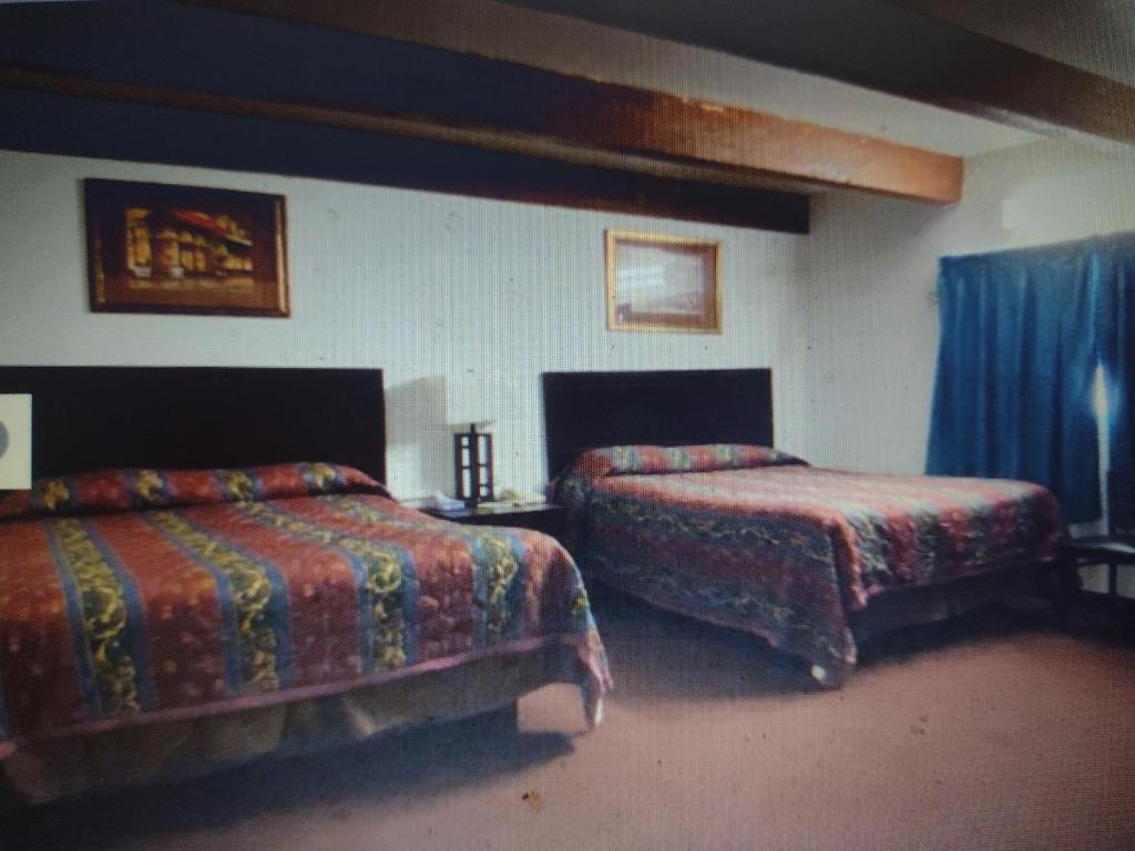 2 camas en una habitación con cortinas azules en Budget Inn & Suites Lowest Price,Best Value!!!, en Freer