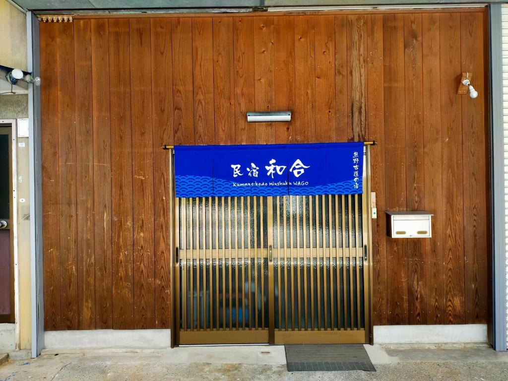eine Tür zu einem Gebäude mit einem blauen Schild darauf in der Unterkunft 民宿 和合 Minshuku WAGO in Tanabe
