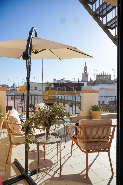a patio with a table and chairs and an umbrella at Cathedral Sevilla Views in Seville