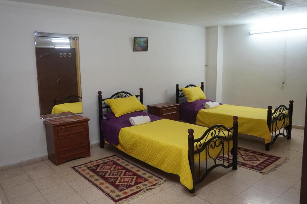a bedroom with two beds with yellow sheets at Lovely Lama Family House in Bethlehem