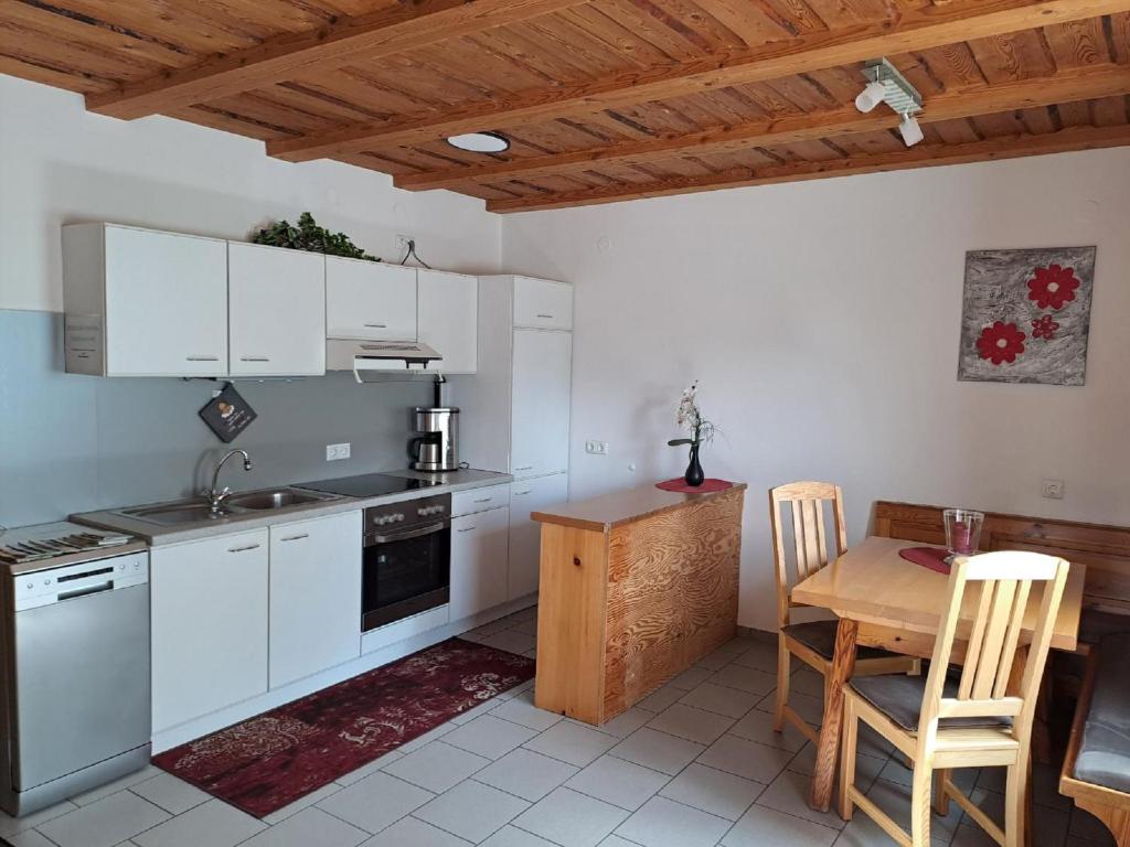 - une cuisine avec des placards blancs, une table et des chaises dans l'établissement Ferienwohnung Gottal Christine, à Neuschönau
