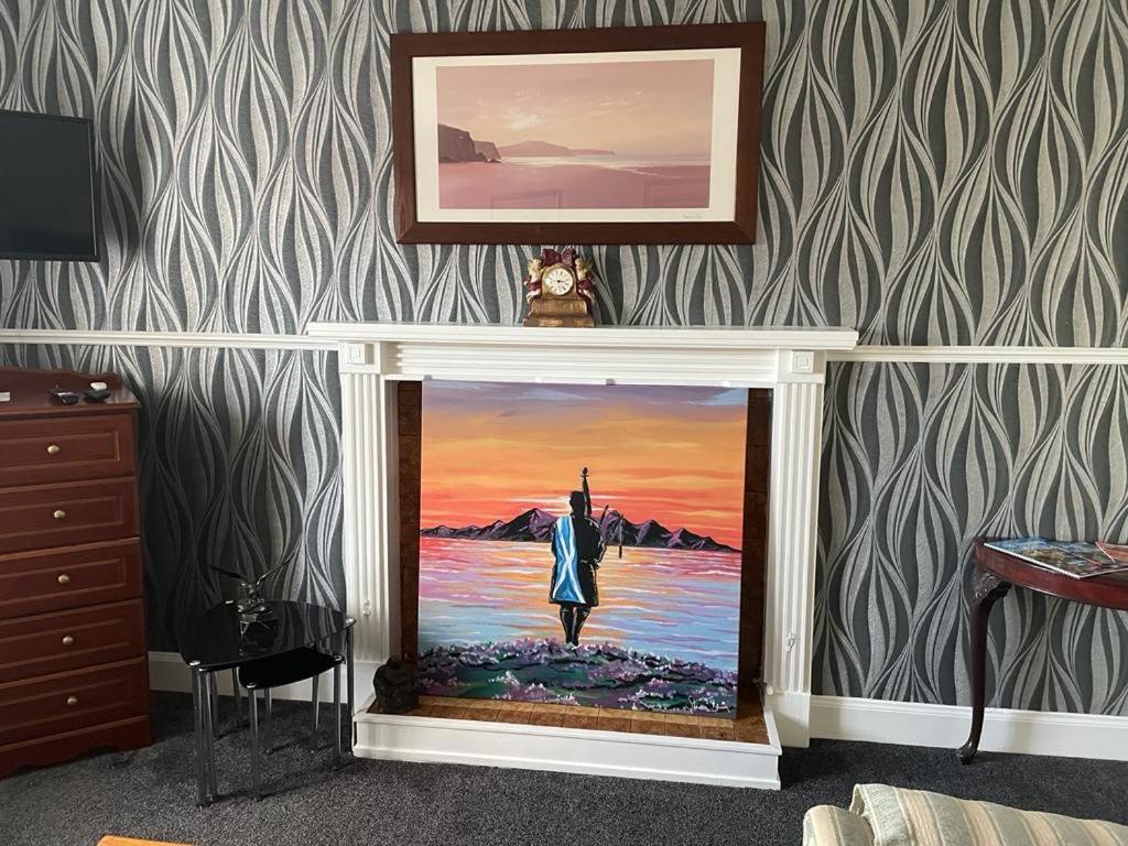 a fireplace with a painting of a woman standing in the water at Clarkes 1st floor Apartment Leslie- Golf Paradies in Leslie