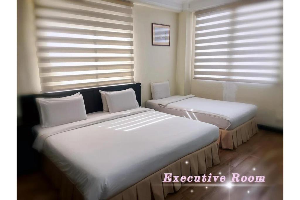 two beds sitting in a room with windows at OYO 90847 Hotel Asia City in Kota Kinabalu