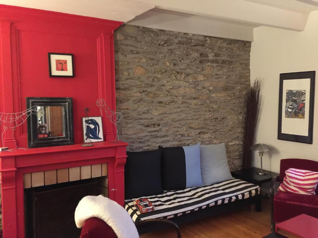 ein Wohnzimmer mit einem Kamin und einer roten Wand in der Unterkunft Maison de famille sur l'île de Groix in Groix
