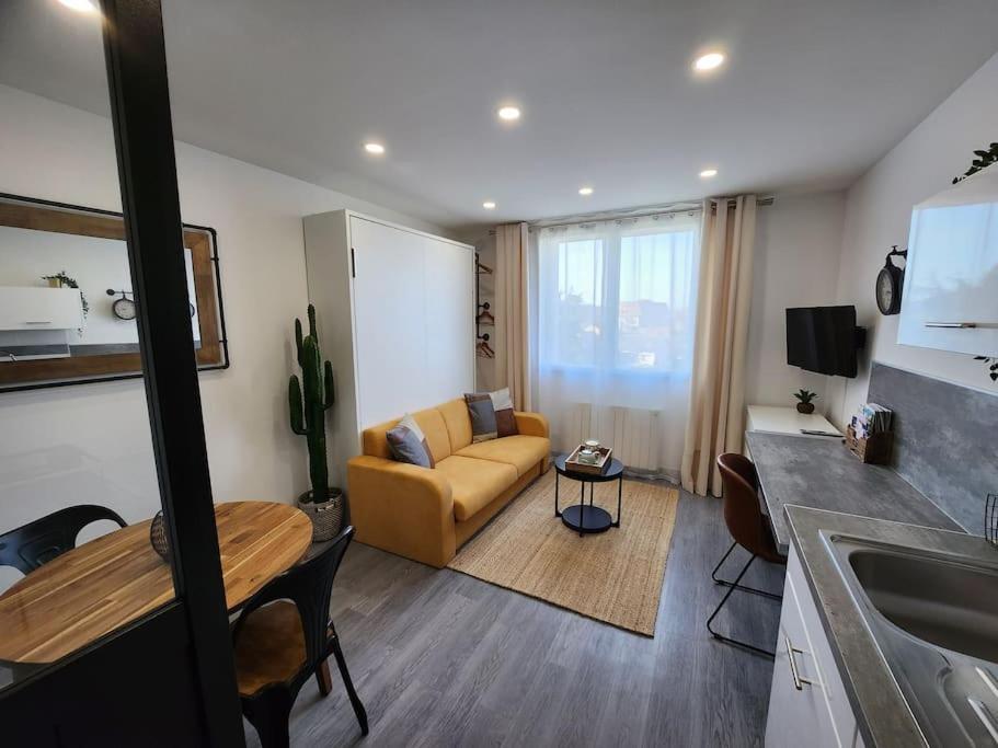 uma sala de estar com um sofá e uma mesa em Le Repaire - Studio avec parking à 550m de la mer em Houlgate