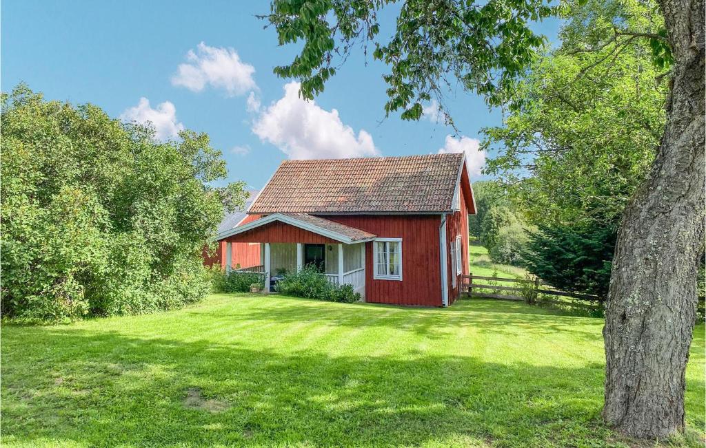 een rood huis in een veld met een boom bij Amazing Home In Vimmerby With Indoor Swimming Pool in Vimmerby