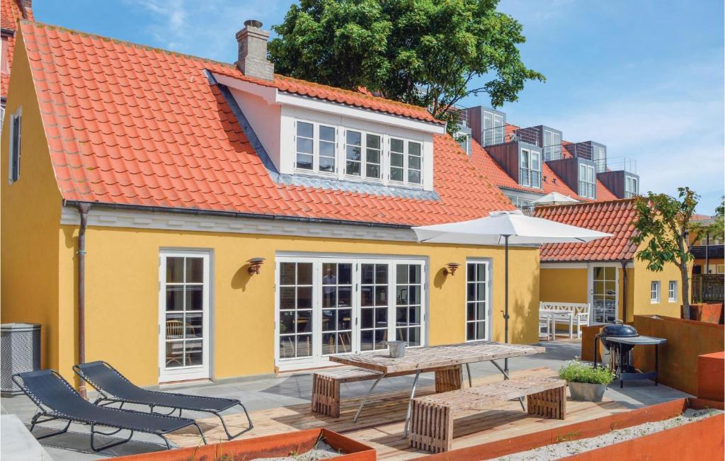 Casa amarilla con mesa, sillas y sombrilla en Matildes Hus, en Skagen