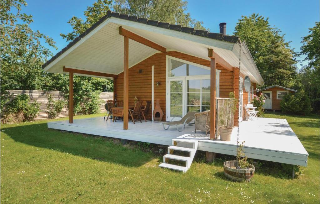 Cette cabane en rondins dispose d'une terrasse couverte, d'une table et de chaises. dans l'établissement Beautiful Home In Grevinge With Kitchen, à Grevinge