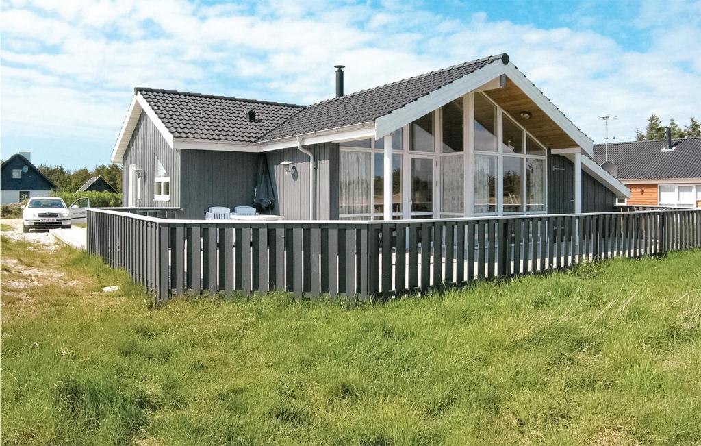 a house with a wooden fence in the grass at Awesome Home In Thisted With 4 Bedrooms, Sauna And Wifi in Nørre Vorupør