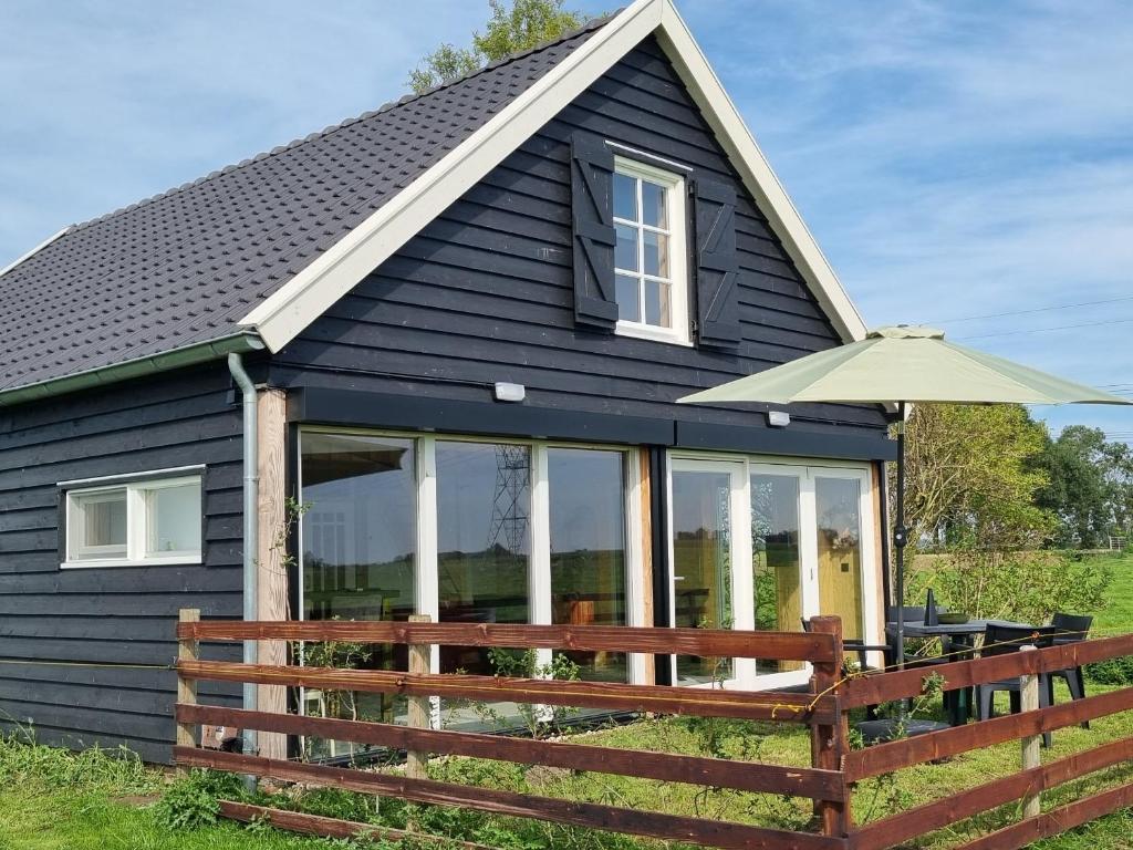 una casa negra con una valla de madera y una sombrilla en GuestHouse Amsterdam "City Farmer" lodge with a skyline view in the countryside en Ámsterdam