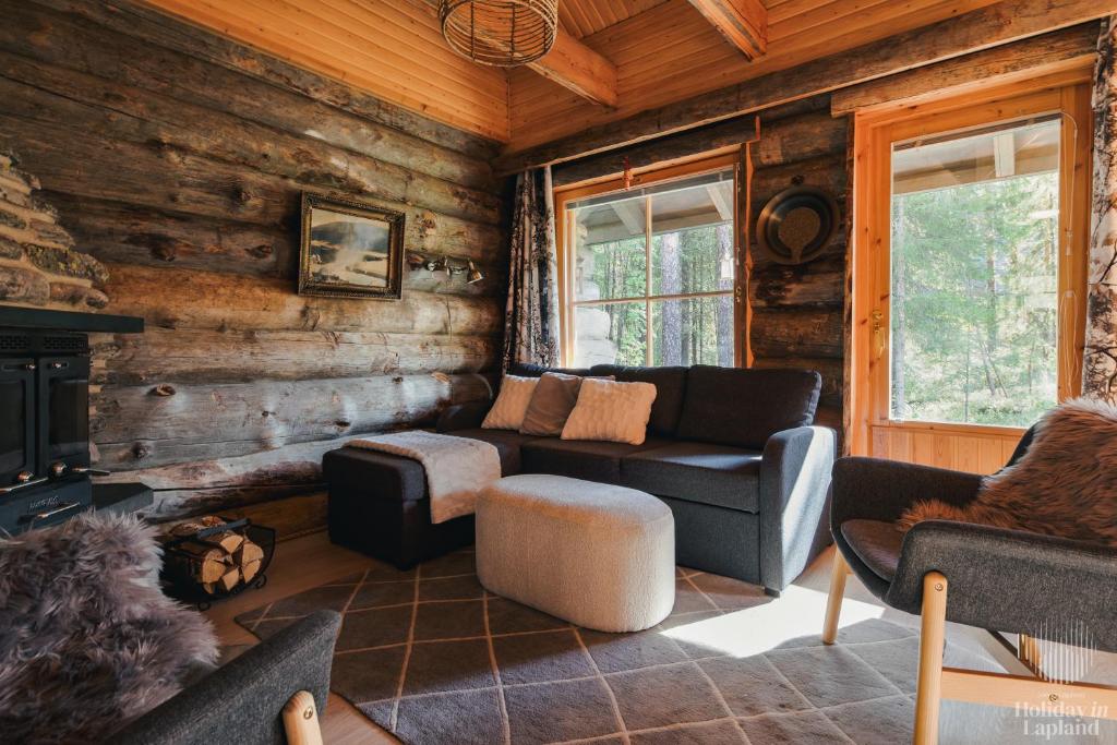ein Wohnzimmer mit einem Sofa und einem Kamin in einer Blockhütte in der Unterkunft Holiday in Lapland - Levin Sudenpesä in Sirkka