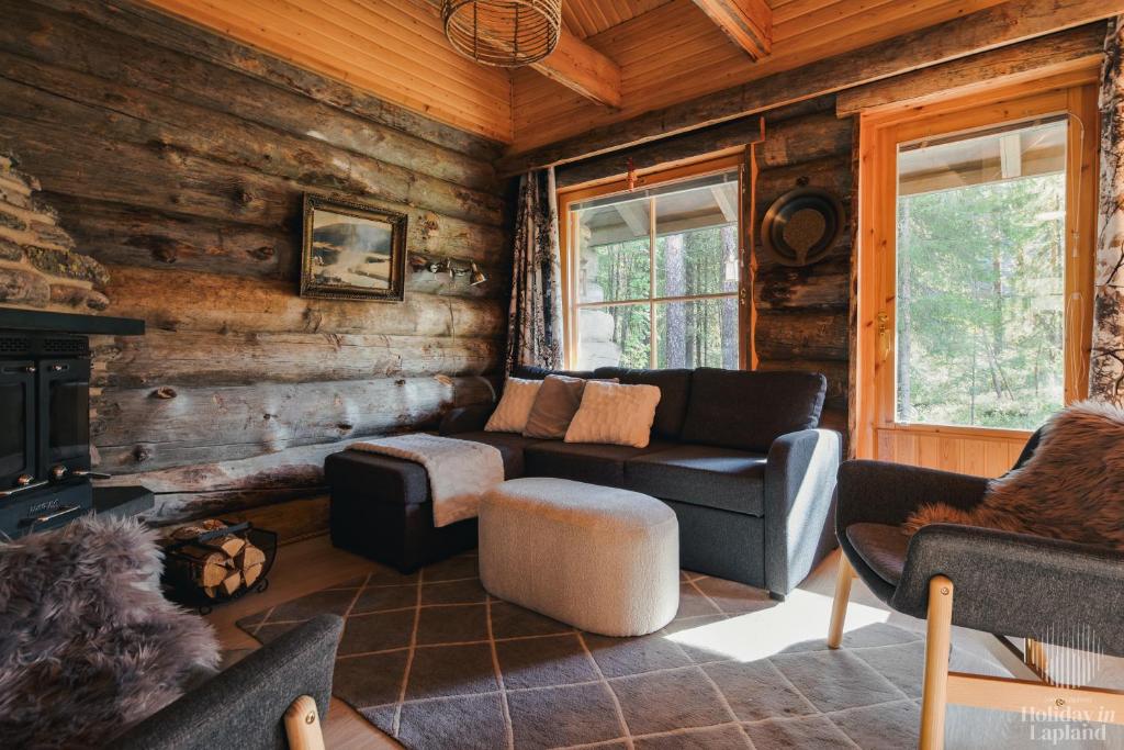 un salon avec un canapé et une cheminée dans une cabane en rondins dans l'établissement Holiday in Lapland - Levin Sudenpesä, à Levi