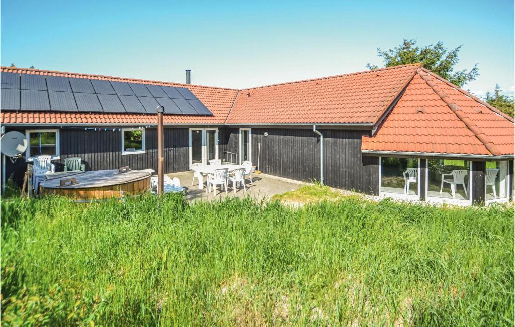 a house with an orange roof and a table and chairs at Amazing Home In Ringkbing With Kitchen in Søndervig