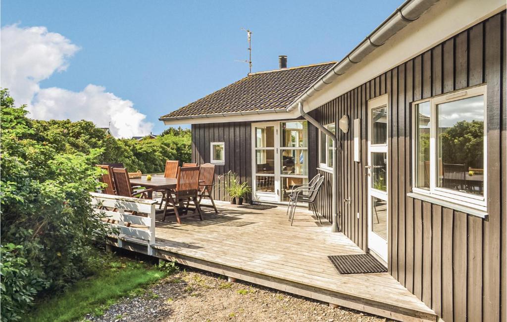 a wooden deck with a table and chairs on a house at 4 Bedroom Cozy Home In Hvide Sande in Havrvig