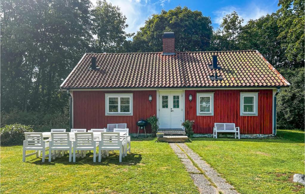 ein rotes Haus mit weißen Tischen und Stühlen davor in der Unterkunft Nice Home In Agunnaryd With Kitchen in Agunnaryd