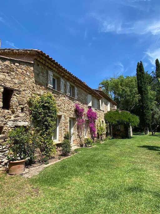 un bâtiment en pierre avec des fleurs sur son côté dans l'établissement Villa provençale familiale avec piscine, à Grimaud