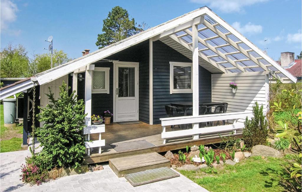 Cette petite maison dispose d'une terrasse couverte en bois et d'une porte blanche. dans l'établissement Awesome Home In Jgerspris With 3 Bedrooms And Wifi, à Jægerspris