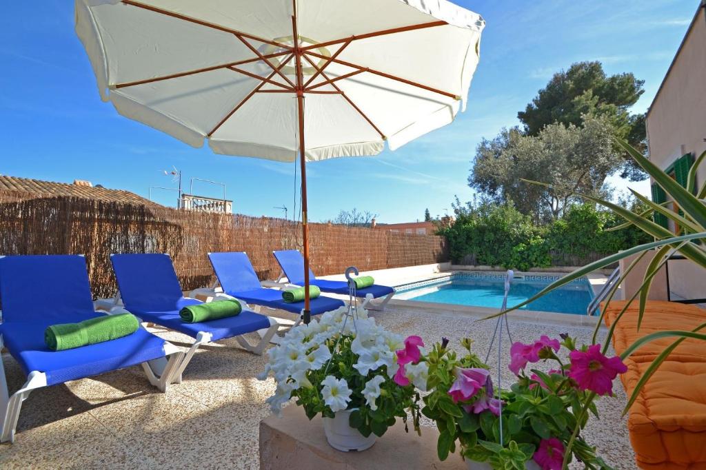 un patio con sillas, una sombrilla y una piscina en Ideal Property Mallorca - Villa Benestar, en El Toro