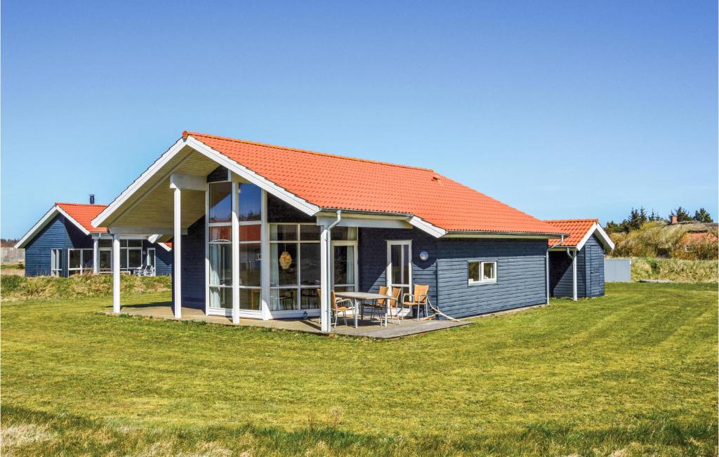una casa blu con un tetto arancione su un campo di Beautiful Home In Ulfborg With 4 Bedrooms And Wifi a Fjand Gårde