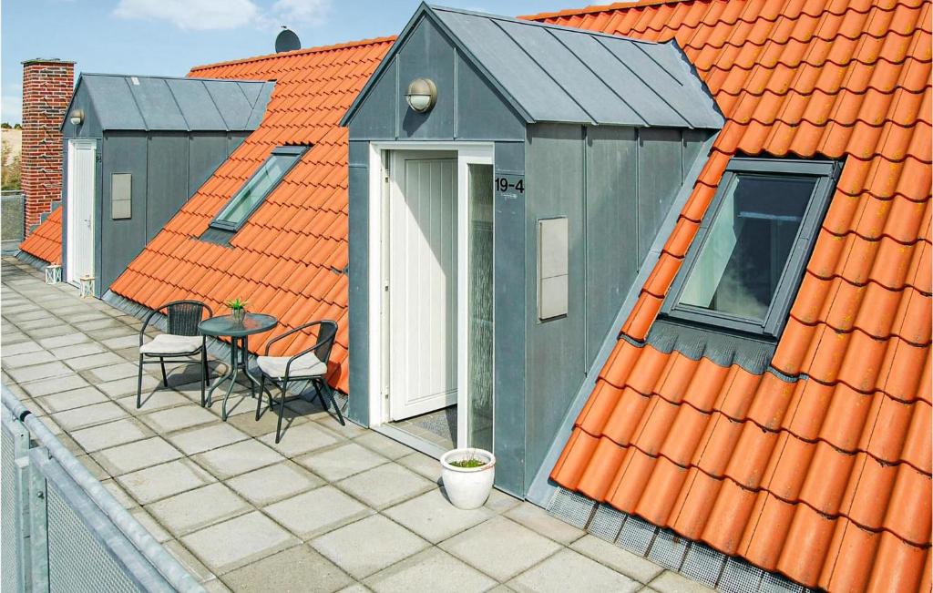 a house with an orange roof with a table and chairs at Gorgeous Apartment In Blvand With Wifi in Blåvand