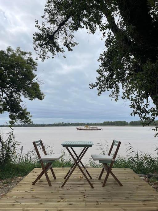 une table de pique-nique et deux chaises sur un quai en bois près d'un lac dans l'établissement Studio au bord de l'eau, à Saint-Seurin-de-Bourg