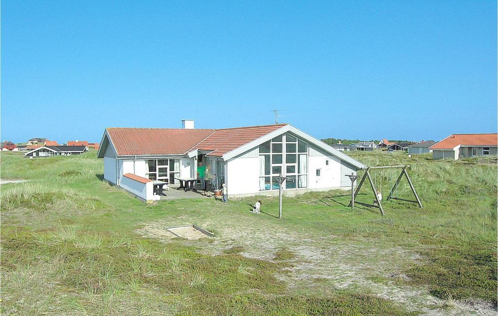 a house in a field with a dog in front of it at Nice Home In Thisted With Indoor Swimming Pool in Klitmøller