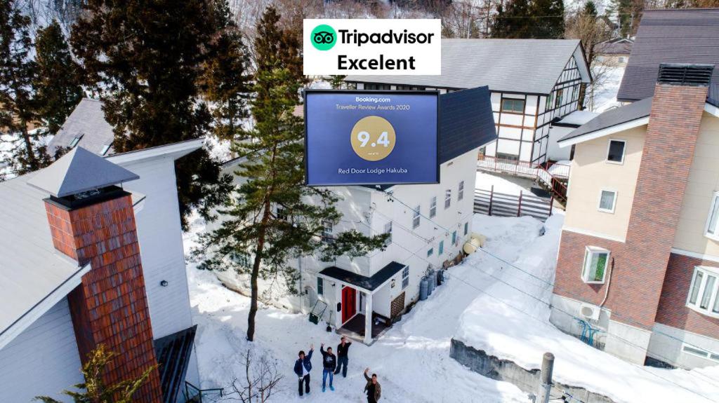 a group of people standing in the snow next to buildings at Red Door Lodge Hakuba in Hakuba