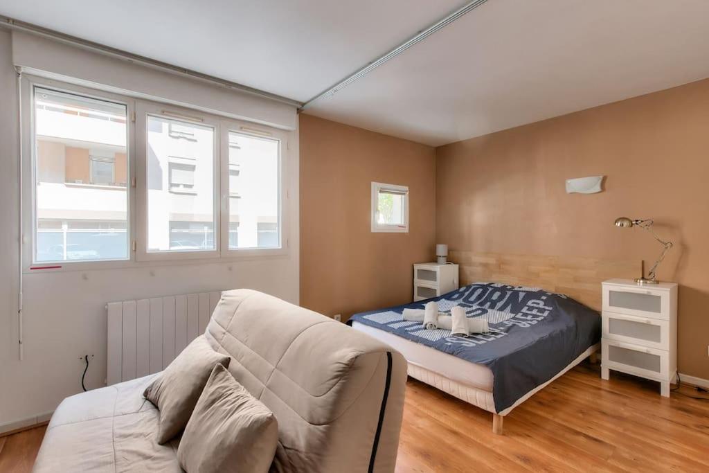 een slaapkamer met een bed en een bank erin bij Cosy studio à proximité du Parc Sergent Blandan in Lyon