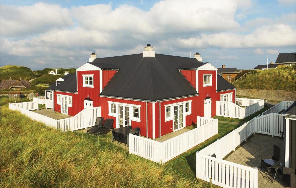 een groot rood huis met een zwart dak bij Klitten in Søndervig