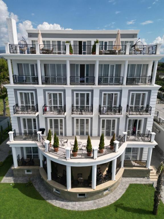 un gran edificio blanco con macetas en los balcones en Грейс Аква Вилла en Sukhum