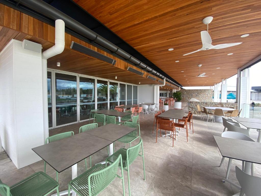 un restaurante con mesas, sillas y ventanas en Resort One Bedroom Apartment, en Pelican Waters