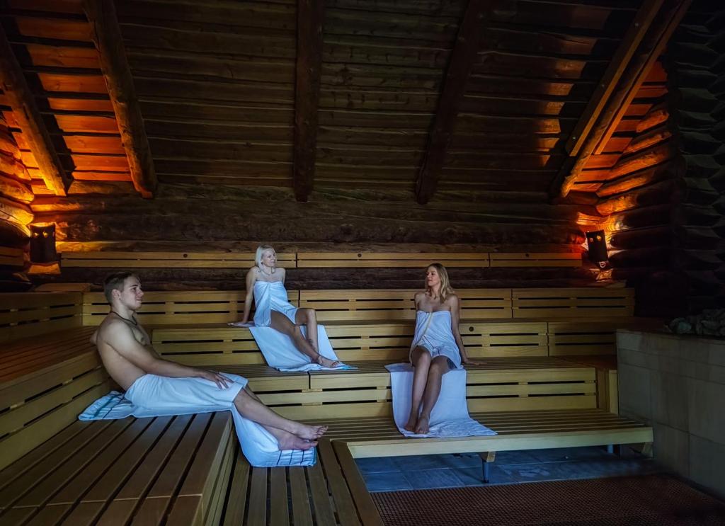 a man and two women sitting in a sauna at Heide Spa Hotel &amp; Resort in Bad Düben