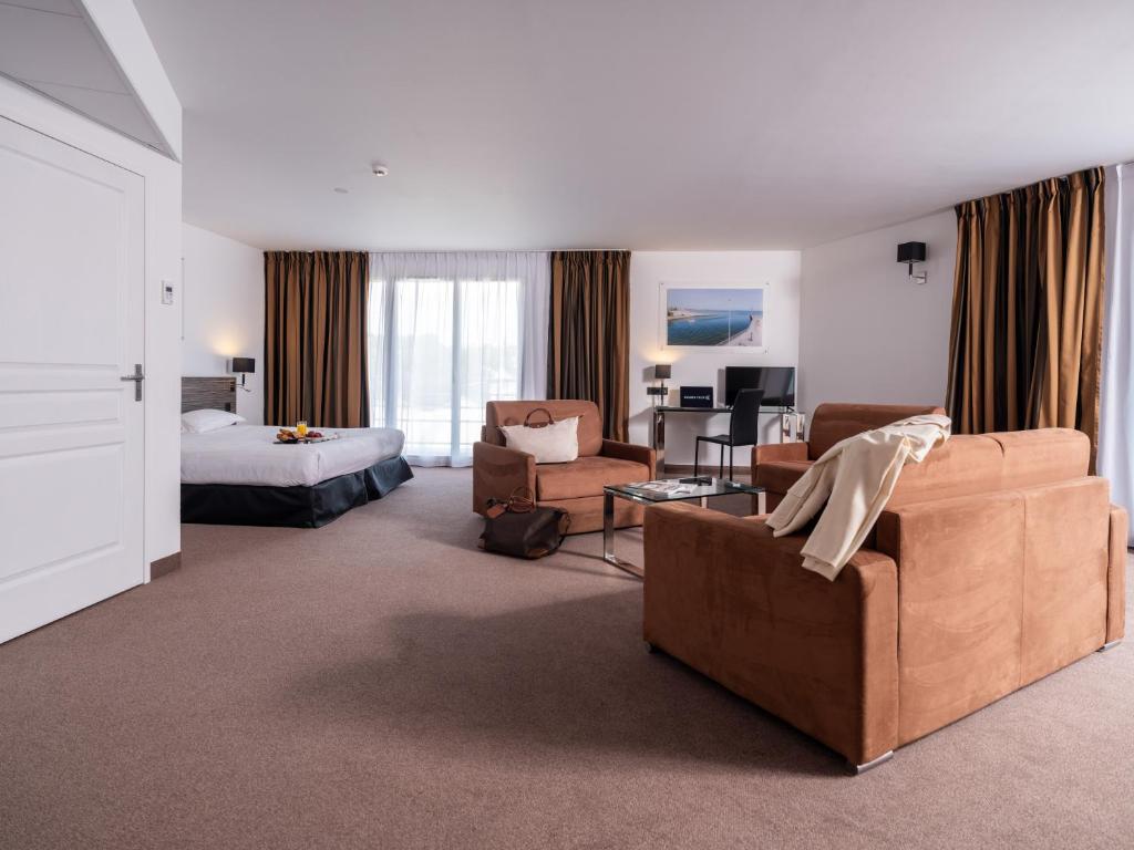 ラ・ボールにあるGolden Tulip La Bauleのベッドとリビングルームが備わるホテルルームです。
