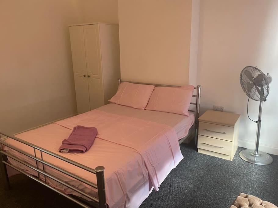 a bedroom with a bed with pink pillows and a fan at Family-Friendly Home in Nottingham in Nottingham