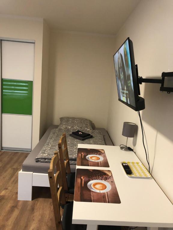 a room with a table and a bed and a television at GottwaldHaus-Freiberg-Apartment / B in Freiberg
