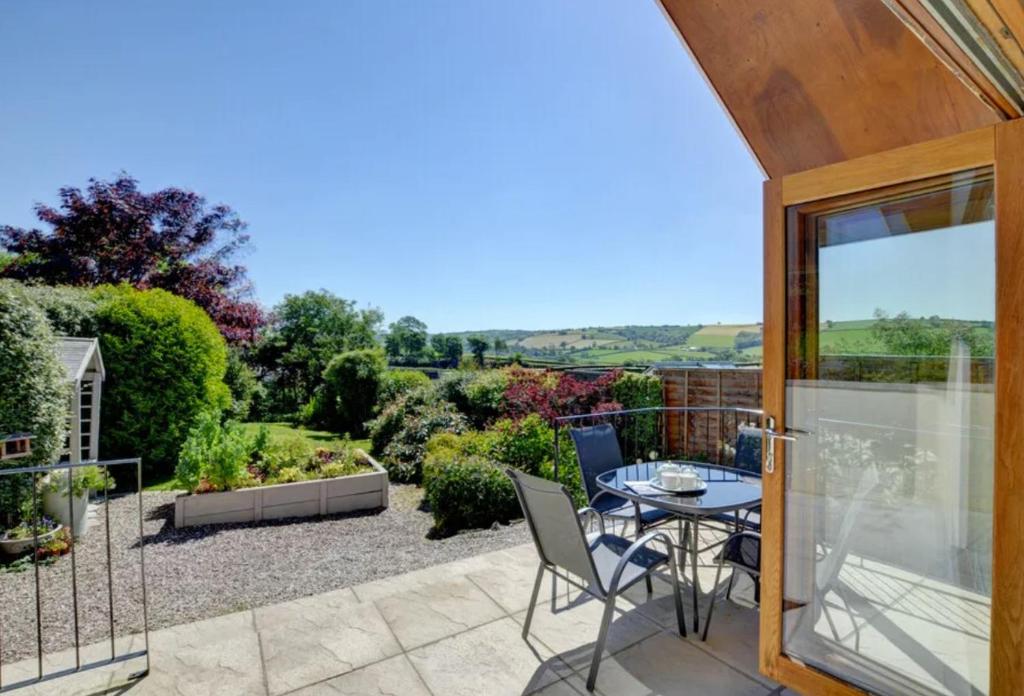 a patio with a table and chairs on a balcony at 2 bed garden cottage nestled on the edge of Exmoor in Bishops Nympton